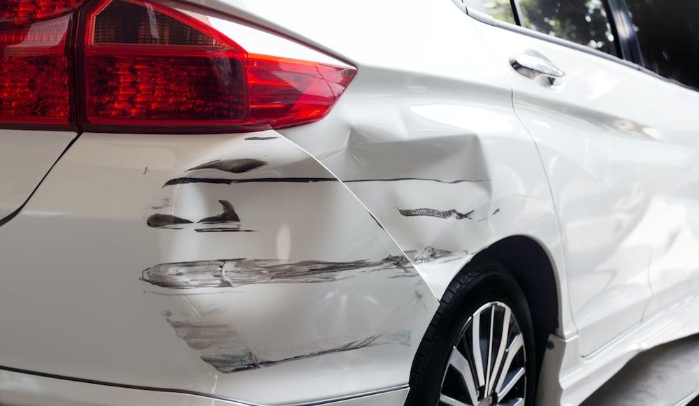 scratched and dented white car