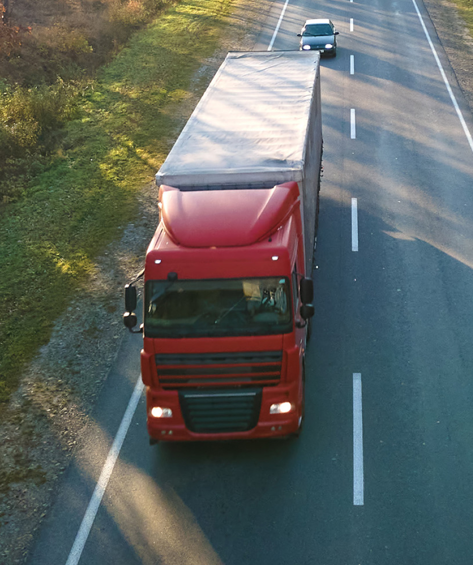 Aerial view of semi-truck with cargo trailer driving on highway