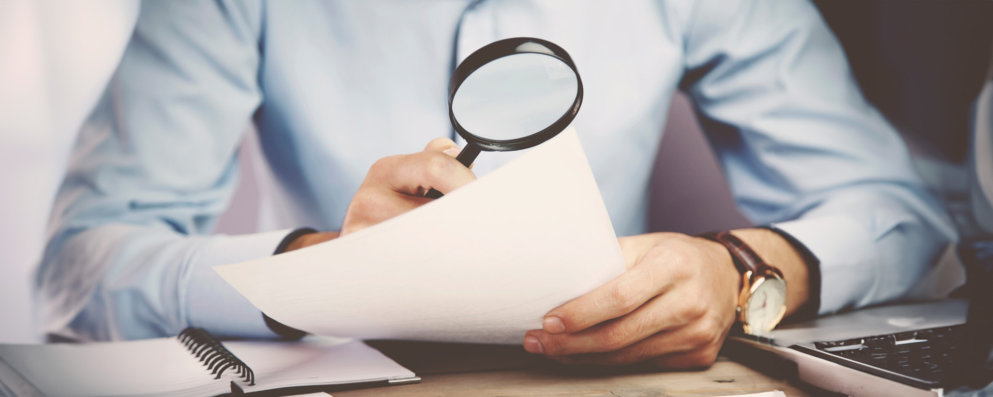 businessman looking through a magnifying glass to documents