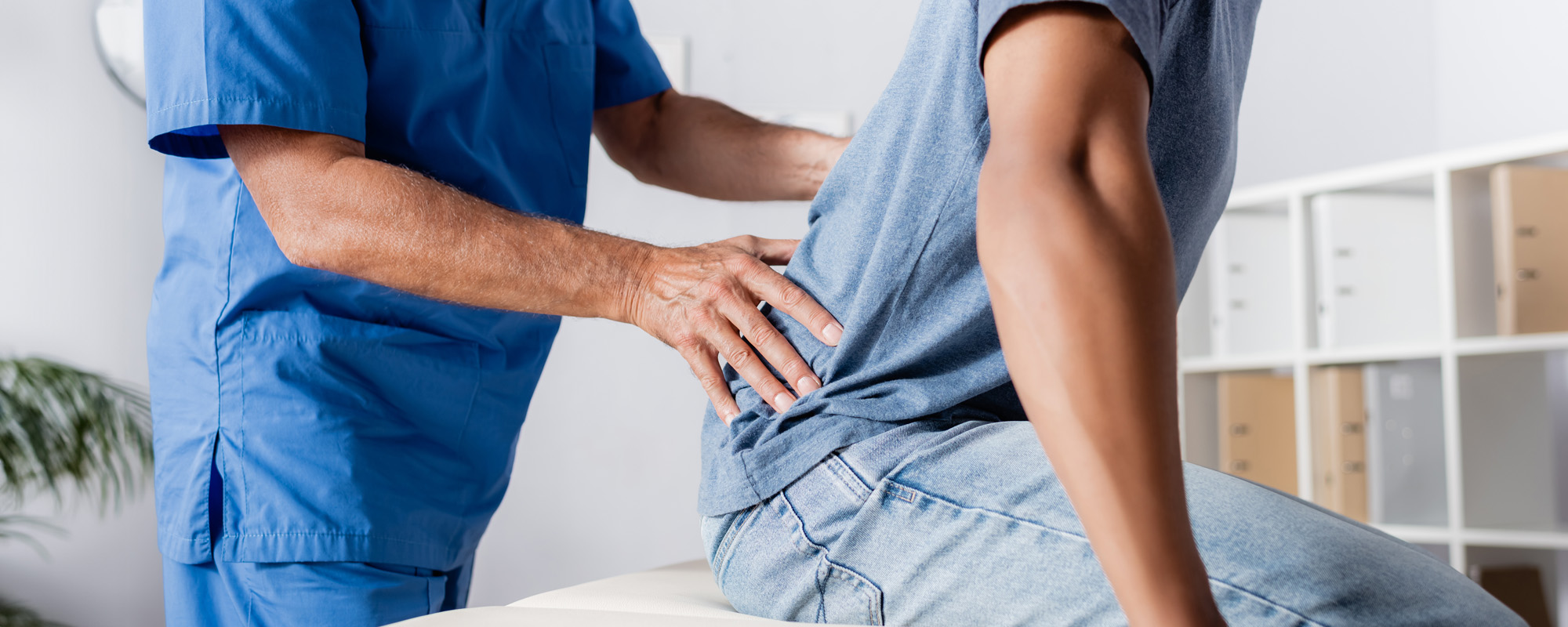 mature chiropractor working with african american man