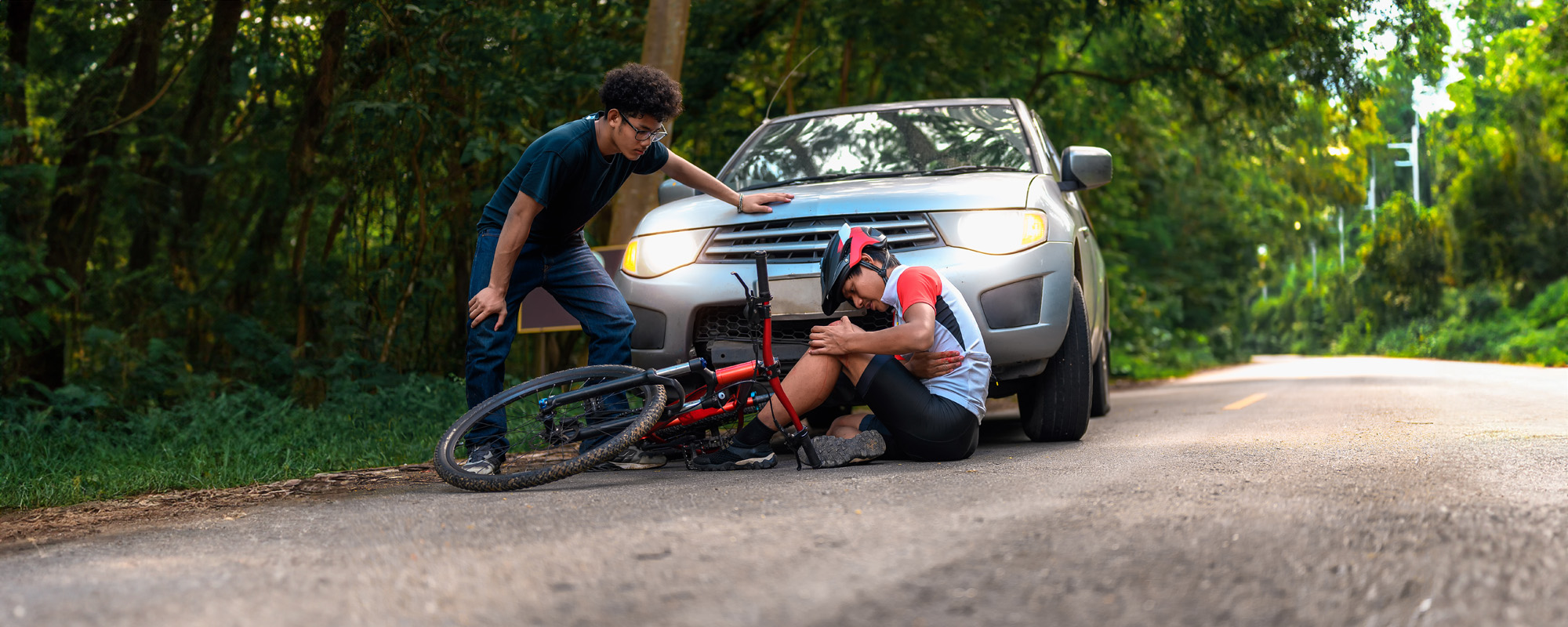 young asian man driving a car crashes into a cyclist