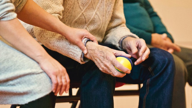 people sitting with elderly man holding ball